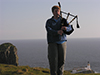 Thumbnail of Nat playing Bagpipes on a clif above the Neist Point Lighthouse